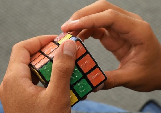 Unsolved tactile Rubik's Cube with 2 hands working it