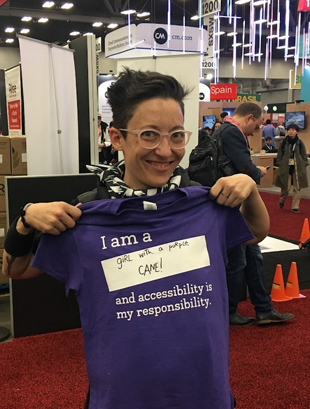 Liz Jackson holds up purple Knowbility t-shirt 