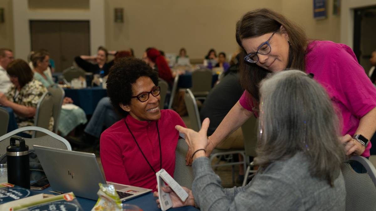 Three attendees chatting at AccessU