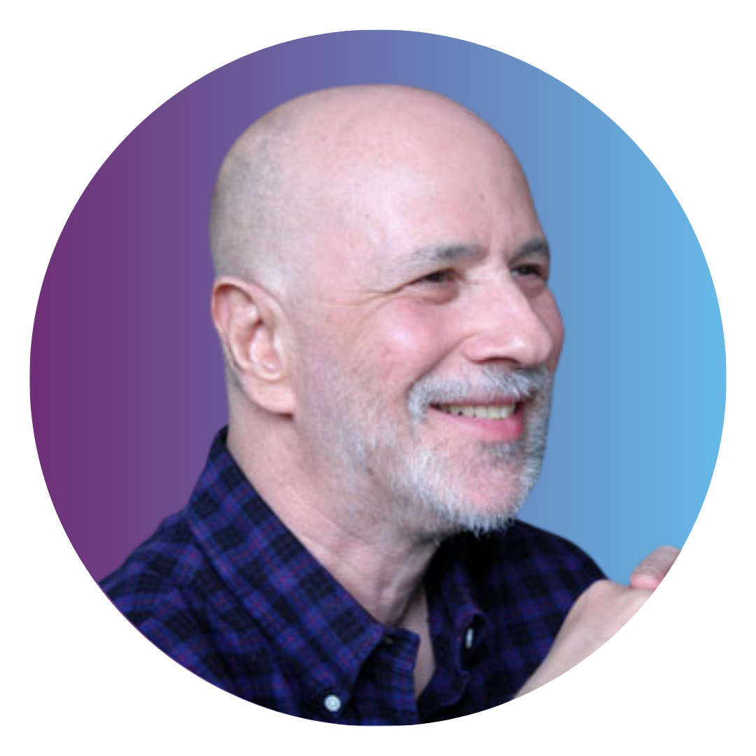 A smiling bald man with a close shaven white beard wearing a blue and purple plaid shirt